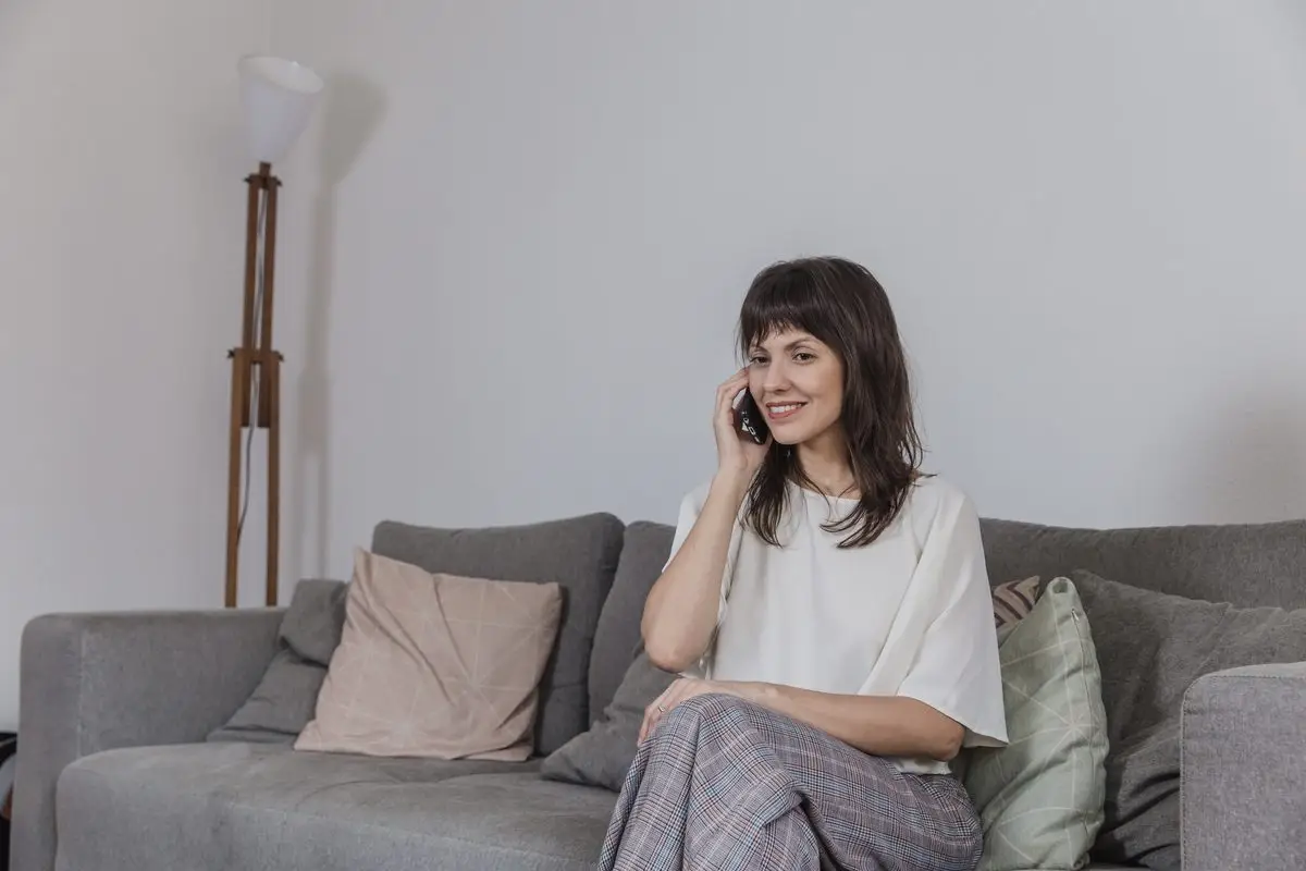 A woman sitting on a sofa taking a phone call at home