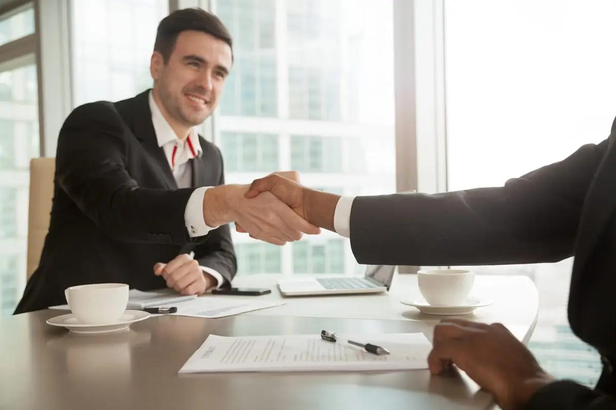 Two adults shaking hands over an agreement