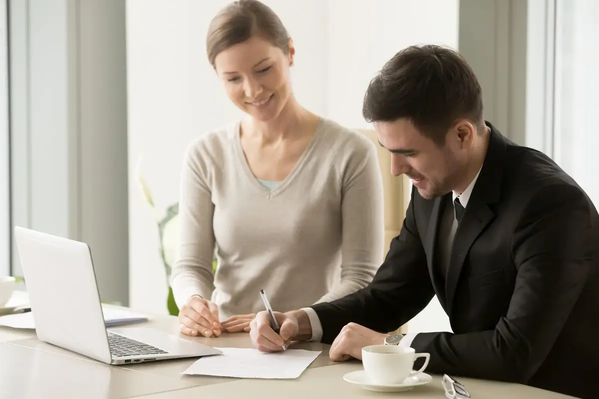 Two people signing a document together