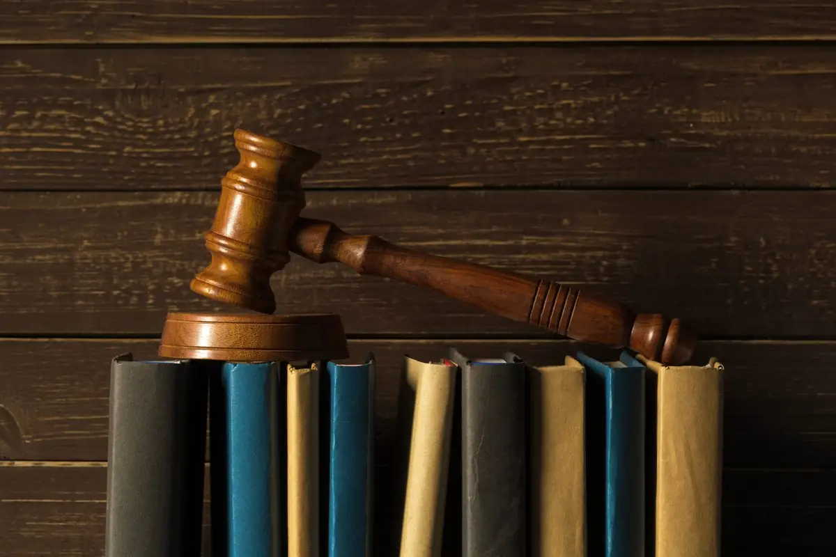 A judge's gavel on a desk beside law books