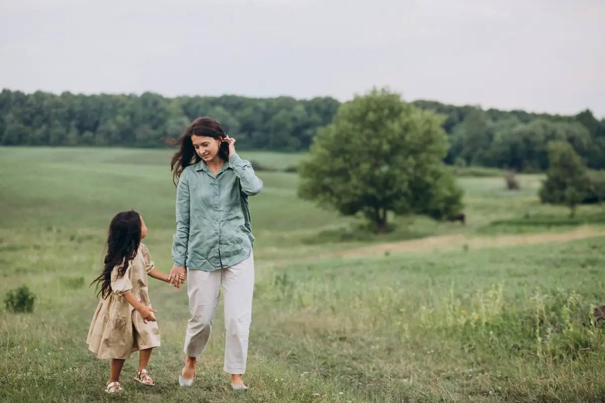 A parent and young child walking hand in hand outdoors