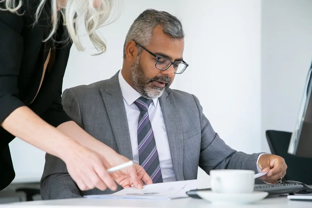 A lawyer going through document details with a client at a desk