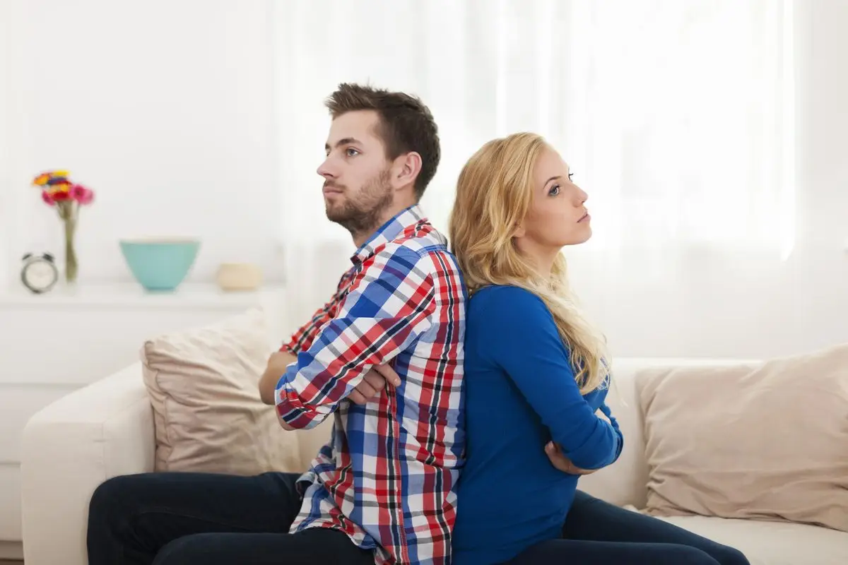 A couple sitting back to back on a sofa, unable to resolve their differences