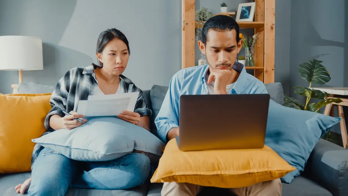 A parent reading court documents on the sofa with a laptop open