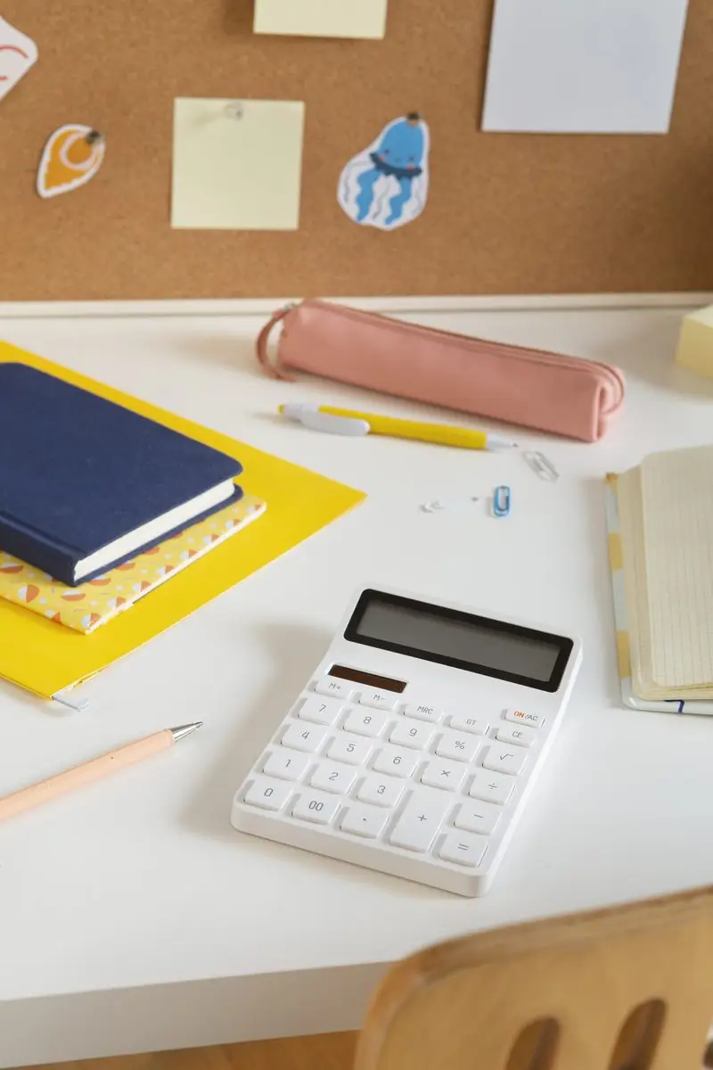 A calculator, notebook and school supplies on a desk while a parent works out child support