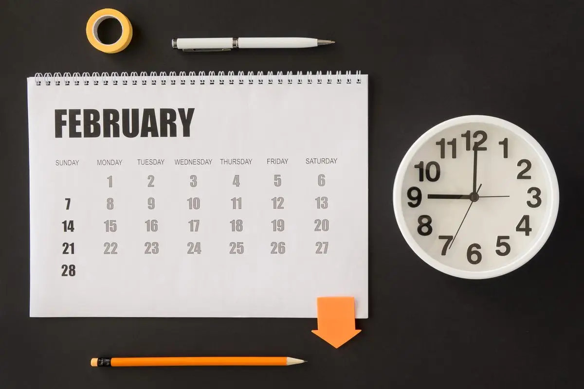 A desk calendar and clock on a dark table, marking the passing of time and the dates a limit runs from