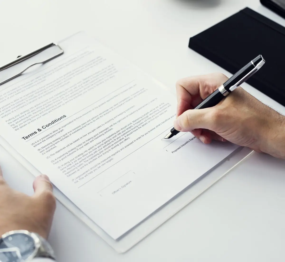 A hand signing a document on a clipboard