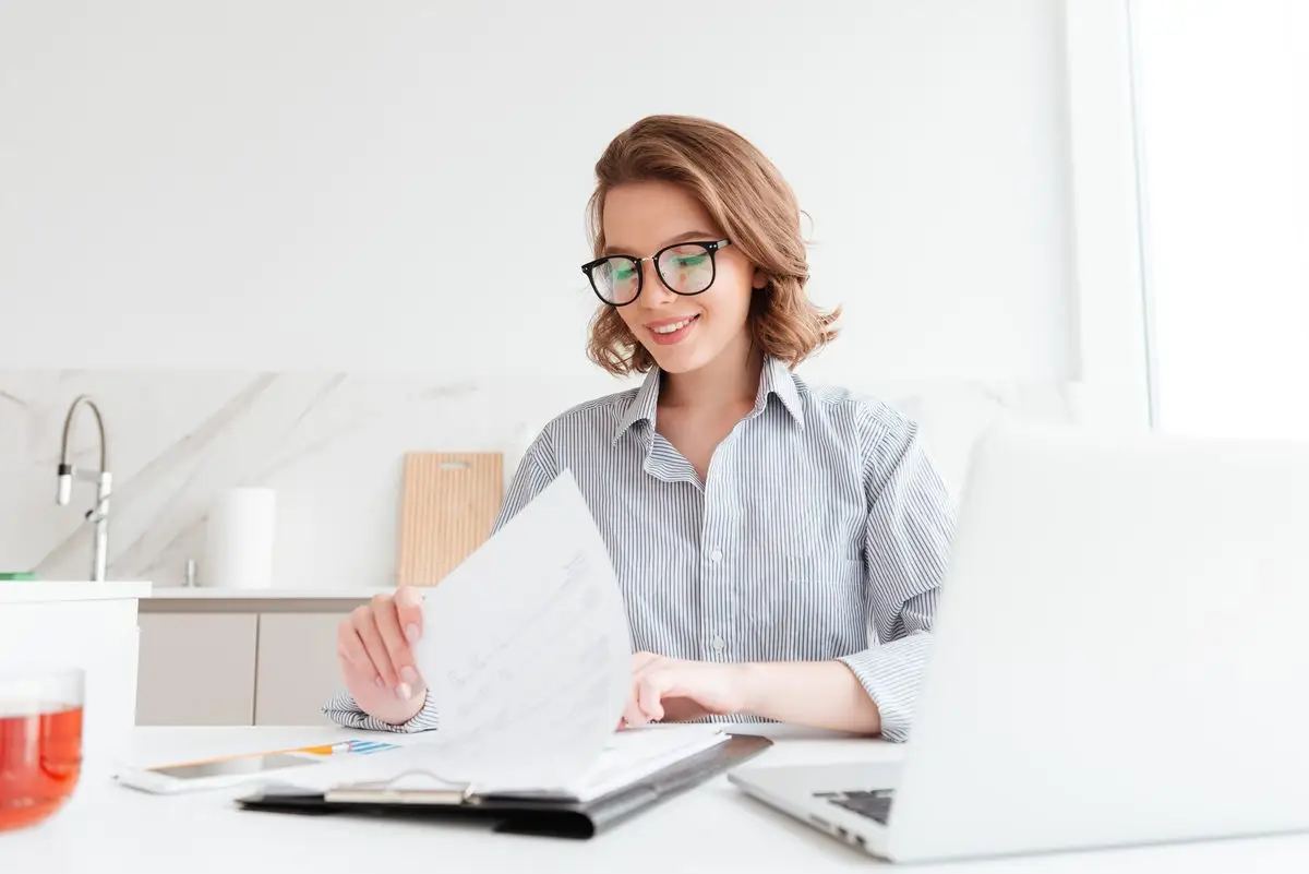 A woman at her kitchen table reading through a contract
