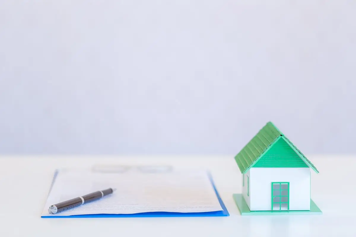 A model house beside a pen and a document on a white surface