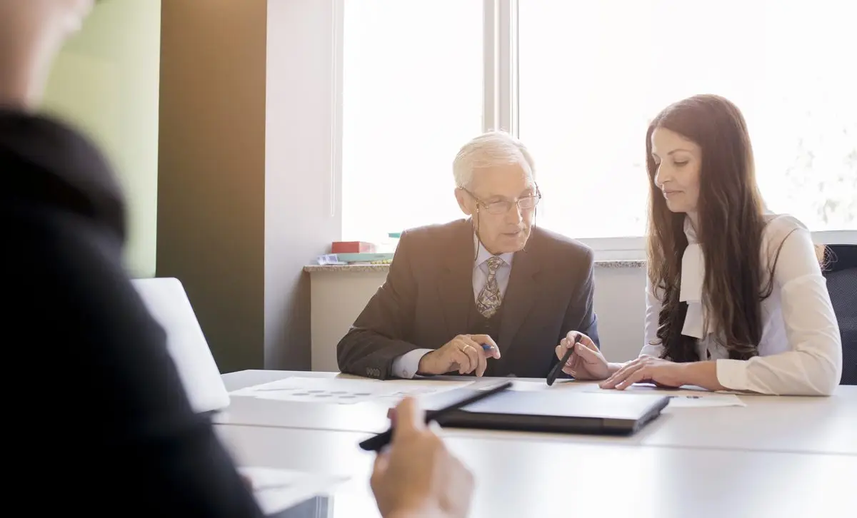 A lawyer in a bright office talking through a document with a client