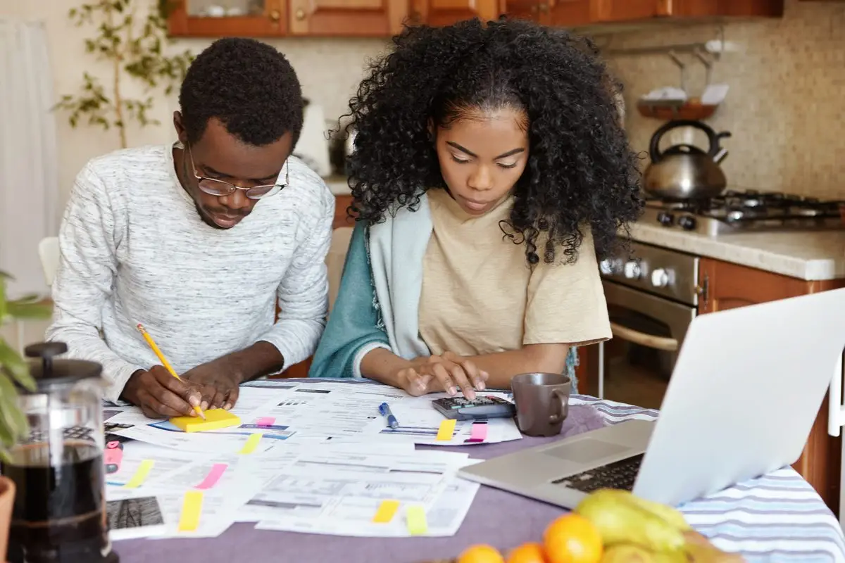 A couple sitting at their kitchen table going through household paperwork and a laptop together