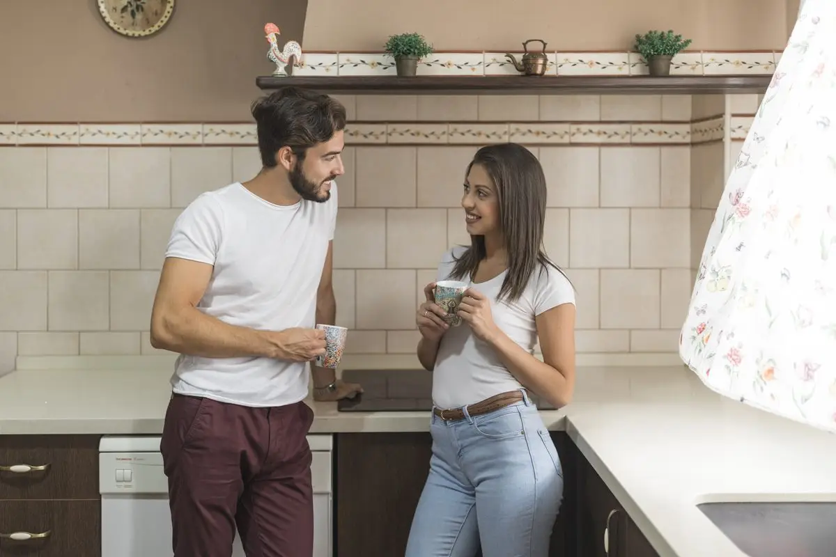 A couple chatting over coffee in their shared kitchen on a weekday morning