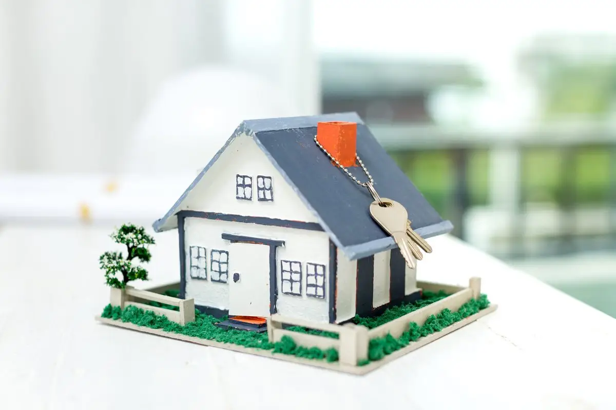 A small model house with keys on a white table