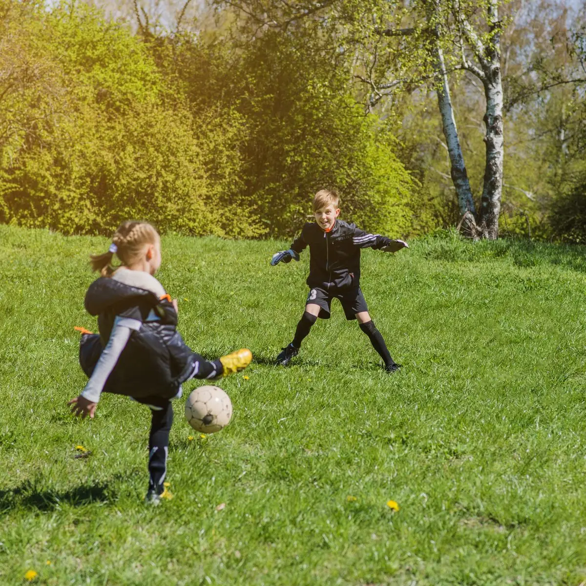 Two children playing soccer in a park