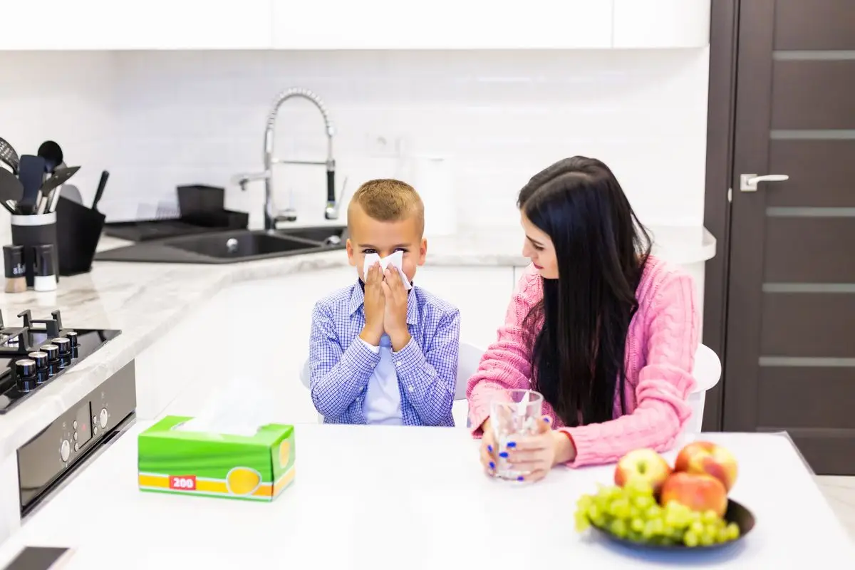 A mother caring for her sick son at the kitchen table