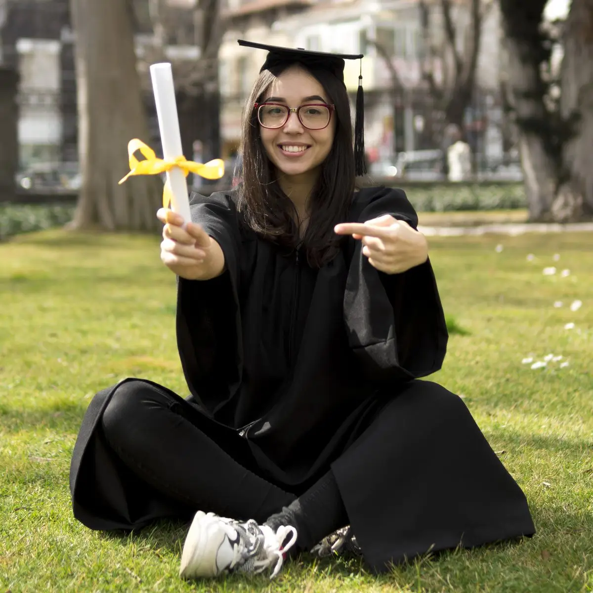 A graduate in cap and gown holding a diploma