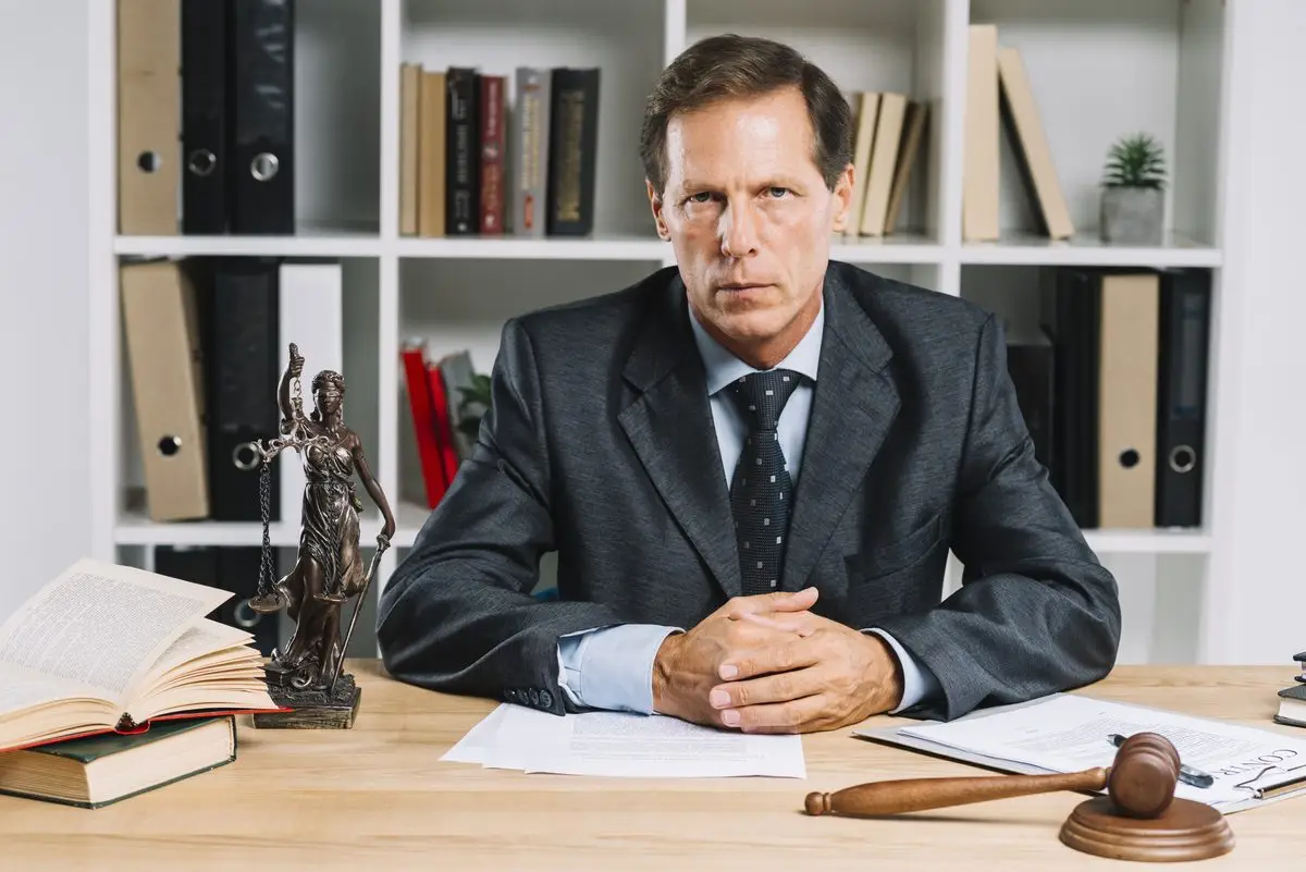 A judge seated at a desk in a courtroom with law books and a gavel