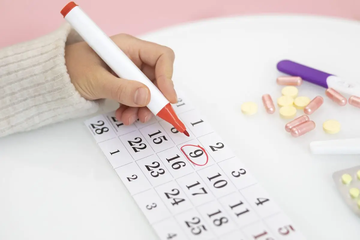 A hand marking a date on a calendar