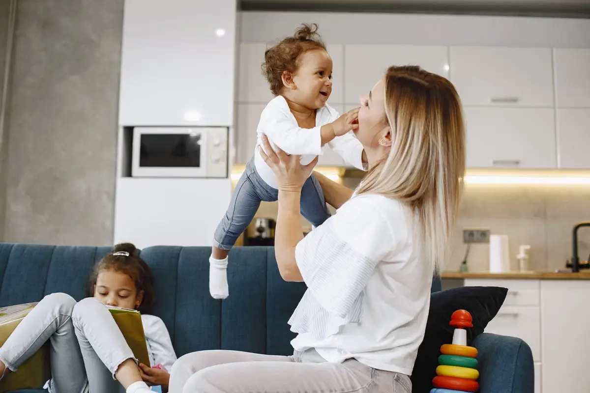 A mother with her baby and older child relaxing on a sofa at home