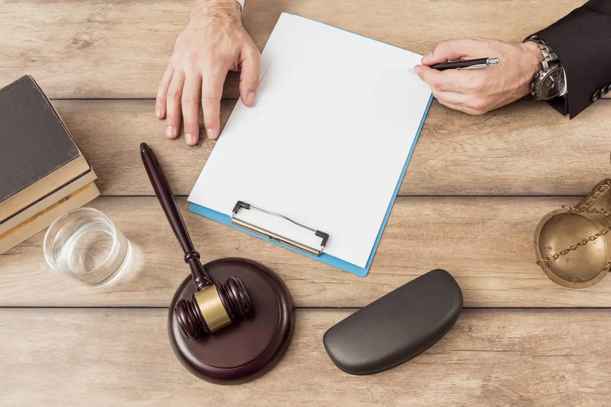 A pen, a clipboard and a judge's gavel on a wooden desk, ready for a court application