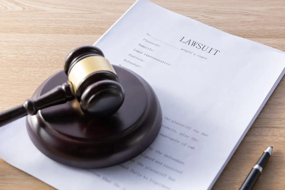 A court application with a gavel and a pen resting on top of the papers