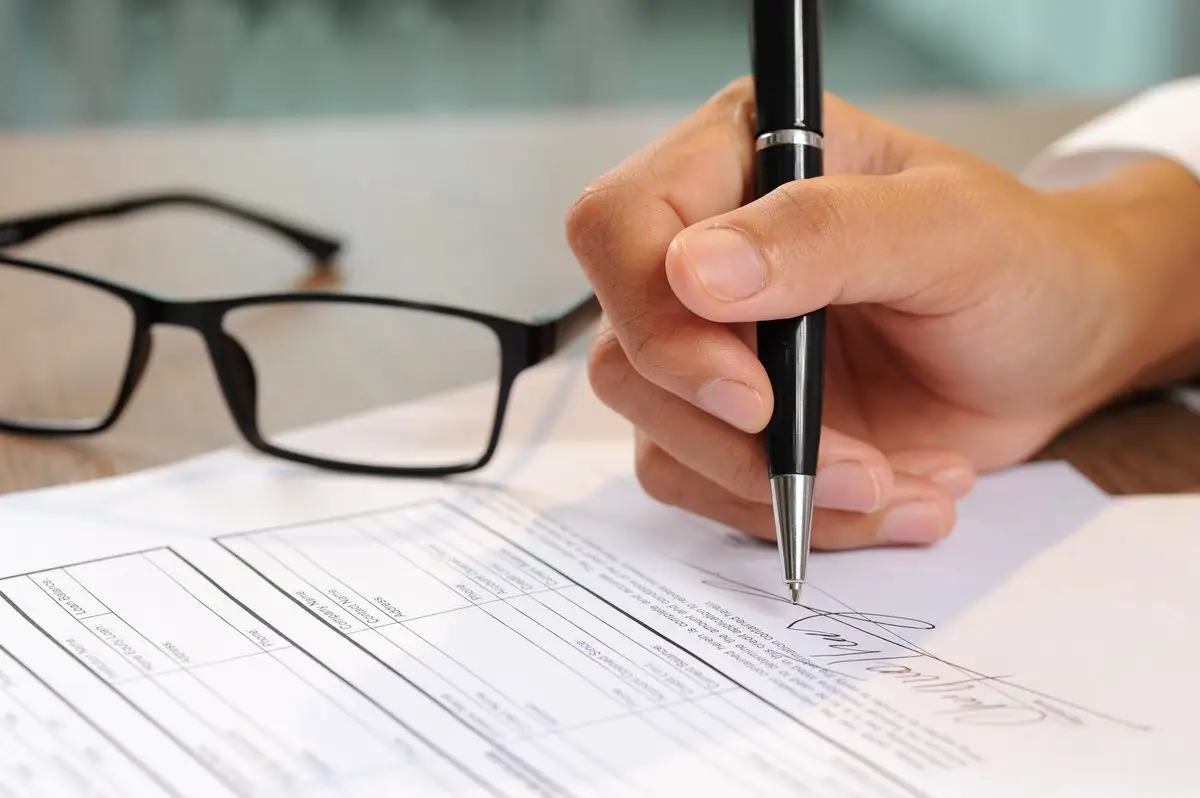 A woman signing a document at a desk