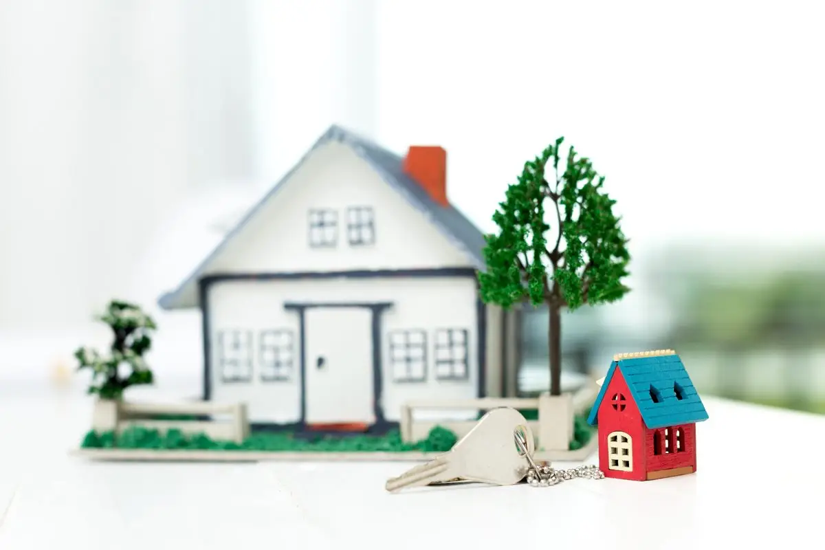 A small model house with a key resting beside it