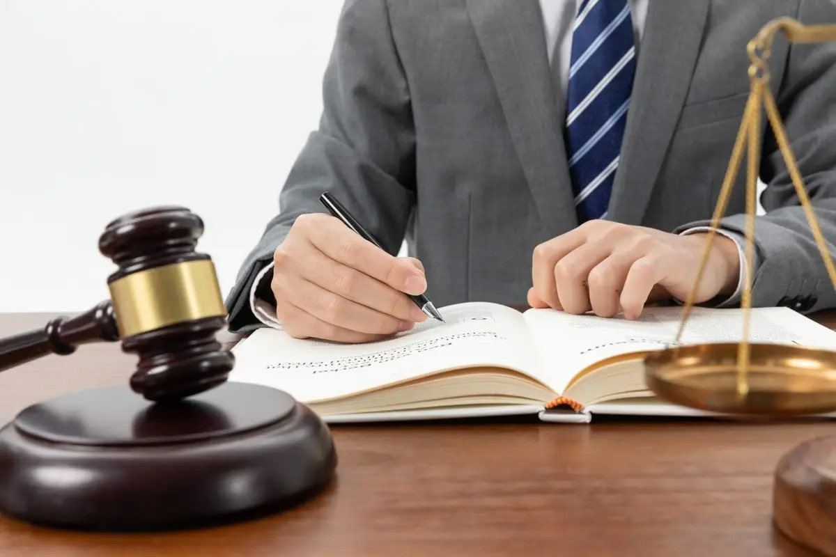 A judge writing in a book beside a gavel and the scales of justice