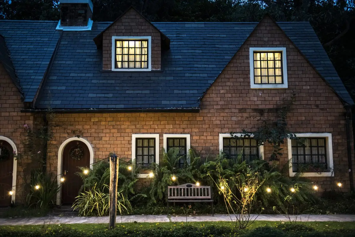 A warmly lit brick family home with lights on in the windows at dusk