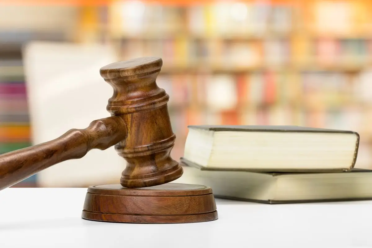 A judge's gavel resting beside law books on a wooden desk