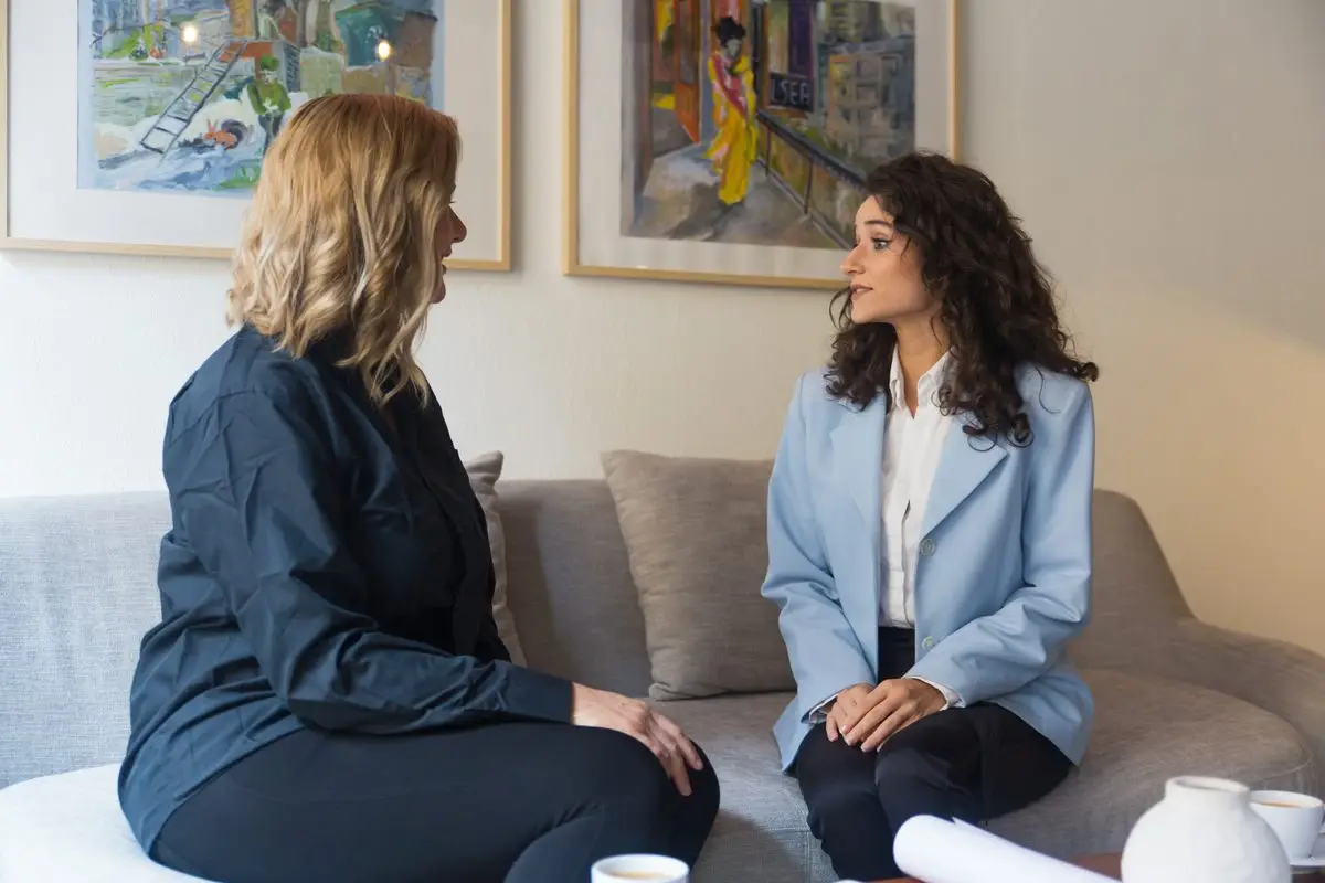 Two women sitting side by side on a sofa having a supportive conversation