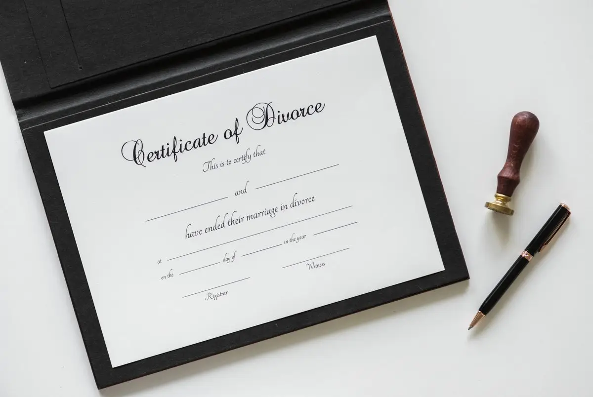 A Certificate of Divorce in a folder with a seal and a pen