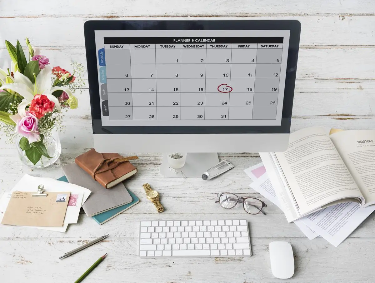 A desk calendar and a clock on a dark desk