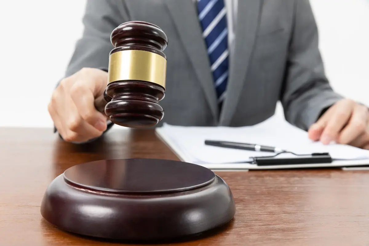 A hand resting on a gavel beside papers and a pen