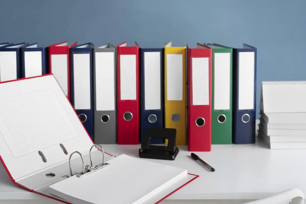 Ring binders and an open binder with a pen on a desk