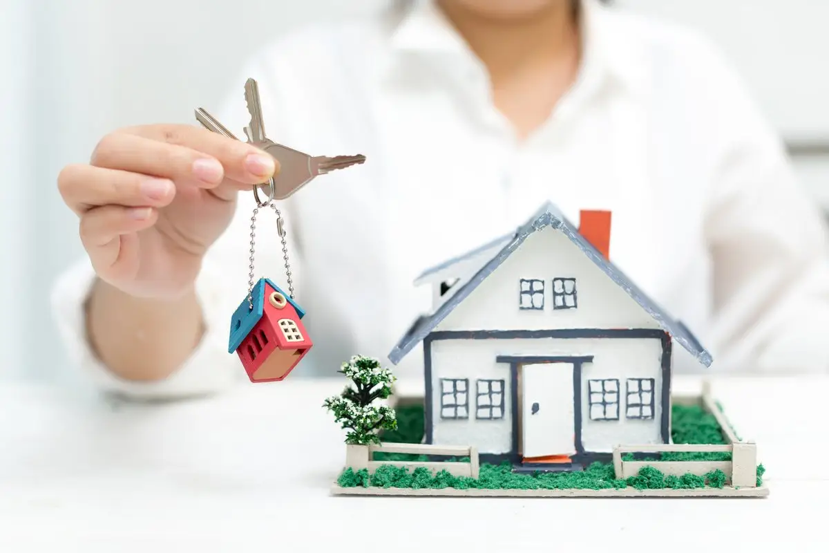 A small model house with a key hanging from it, standing for property claims