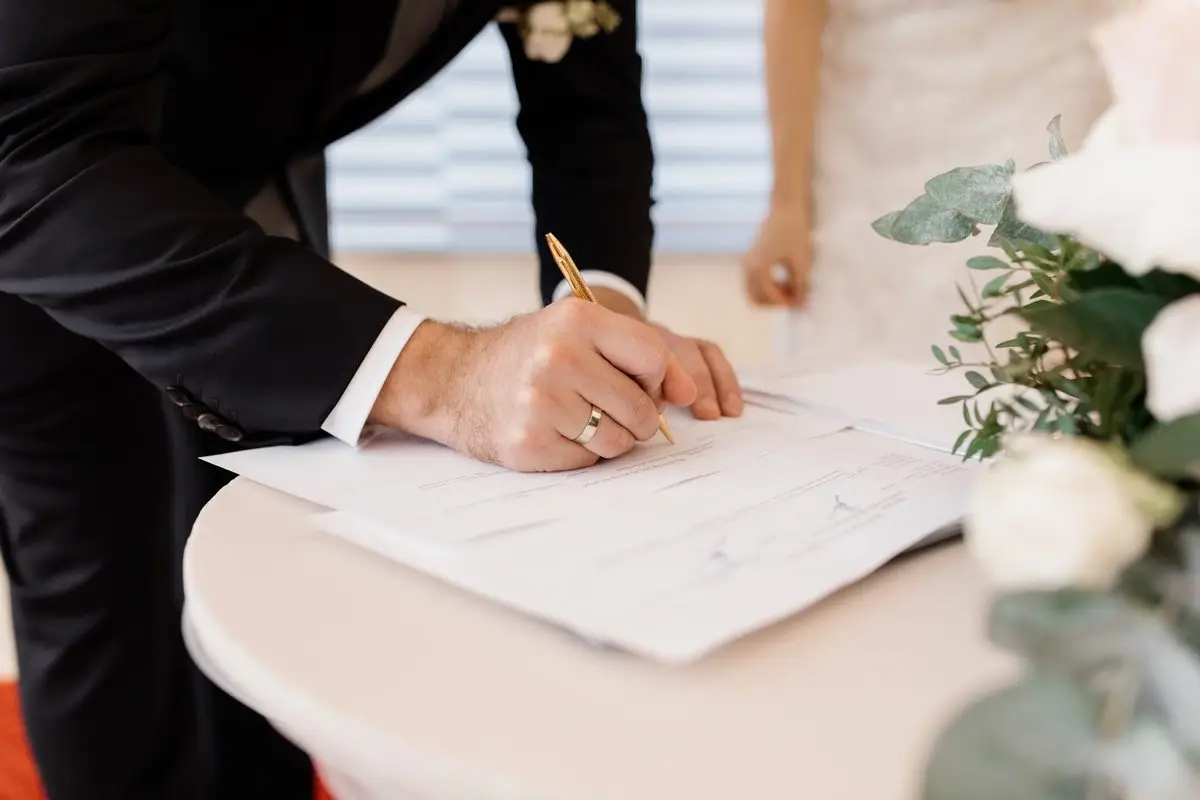 A couple signing marriage documents at a table decorated with flowers
