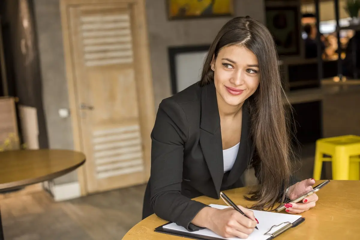 A woman glancing aside as she writes on a document attached to a clipboard