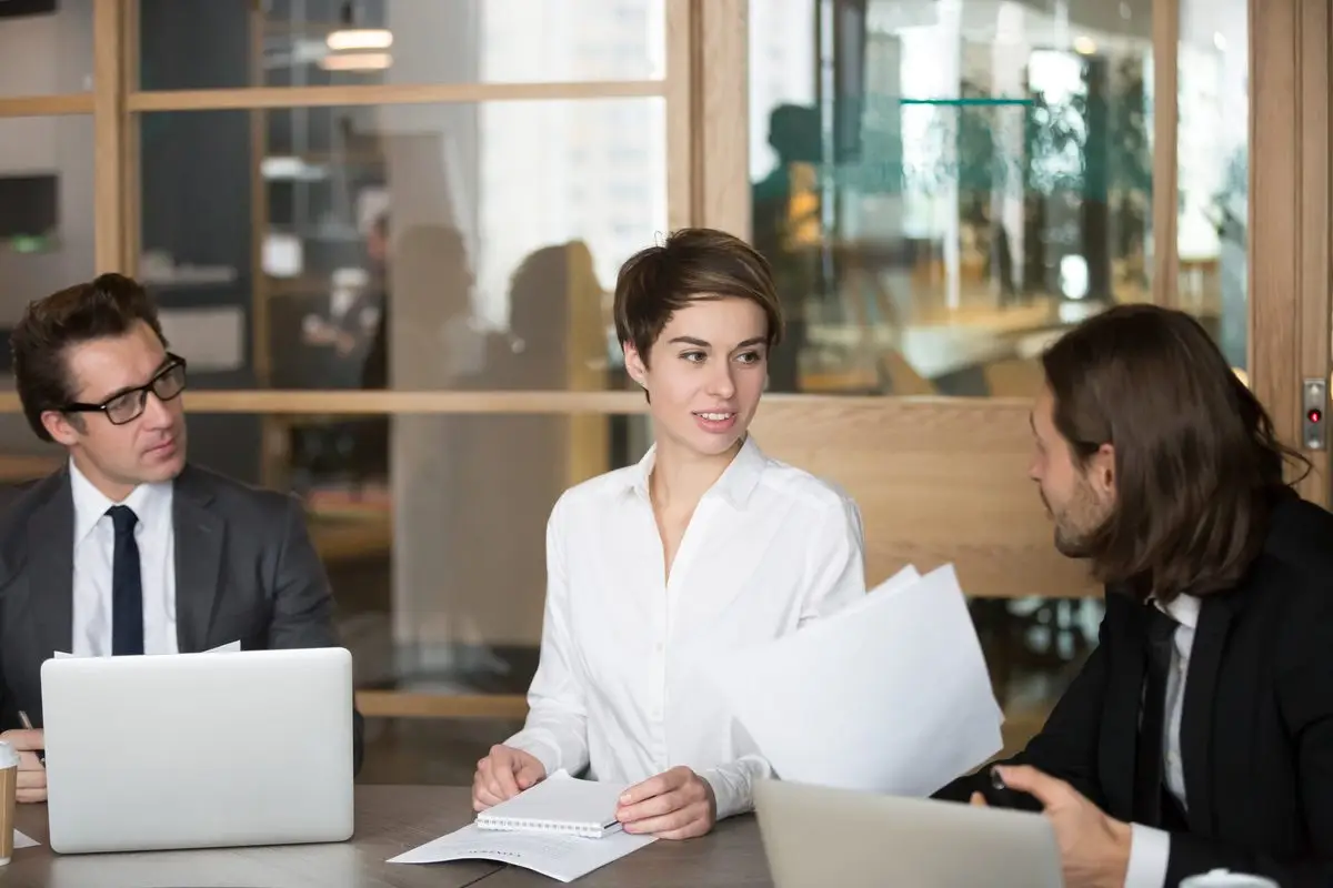 Professionals negotiating around a meeting table with documents and laptops