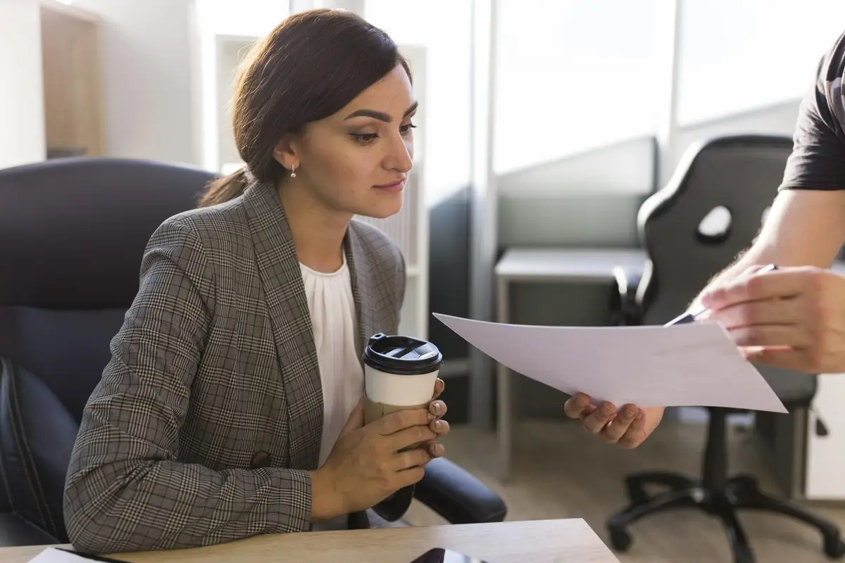 A woman handing a signed document across a table to a consultant