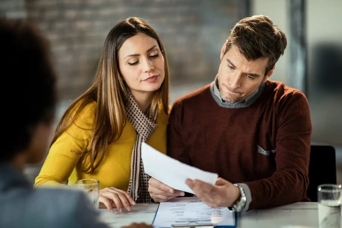 A couple looking over a document together at a table with an adviser