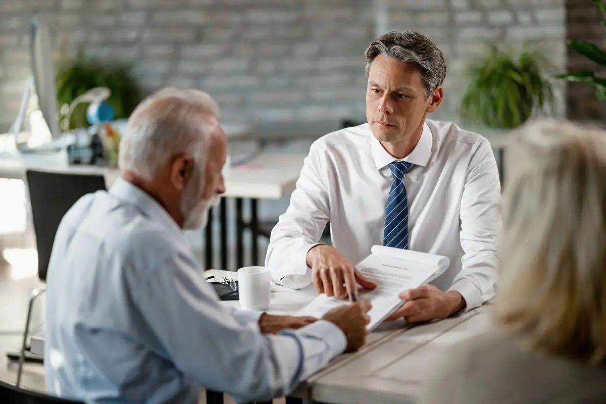 Two people and a professional seated around a table going through papers during a mediation session