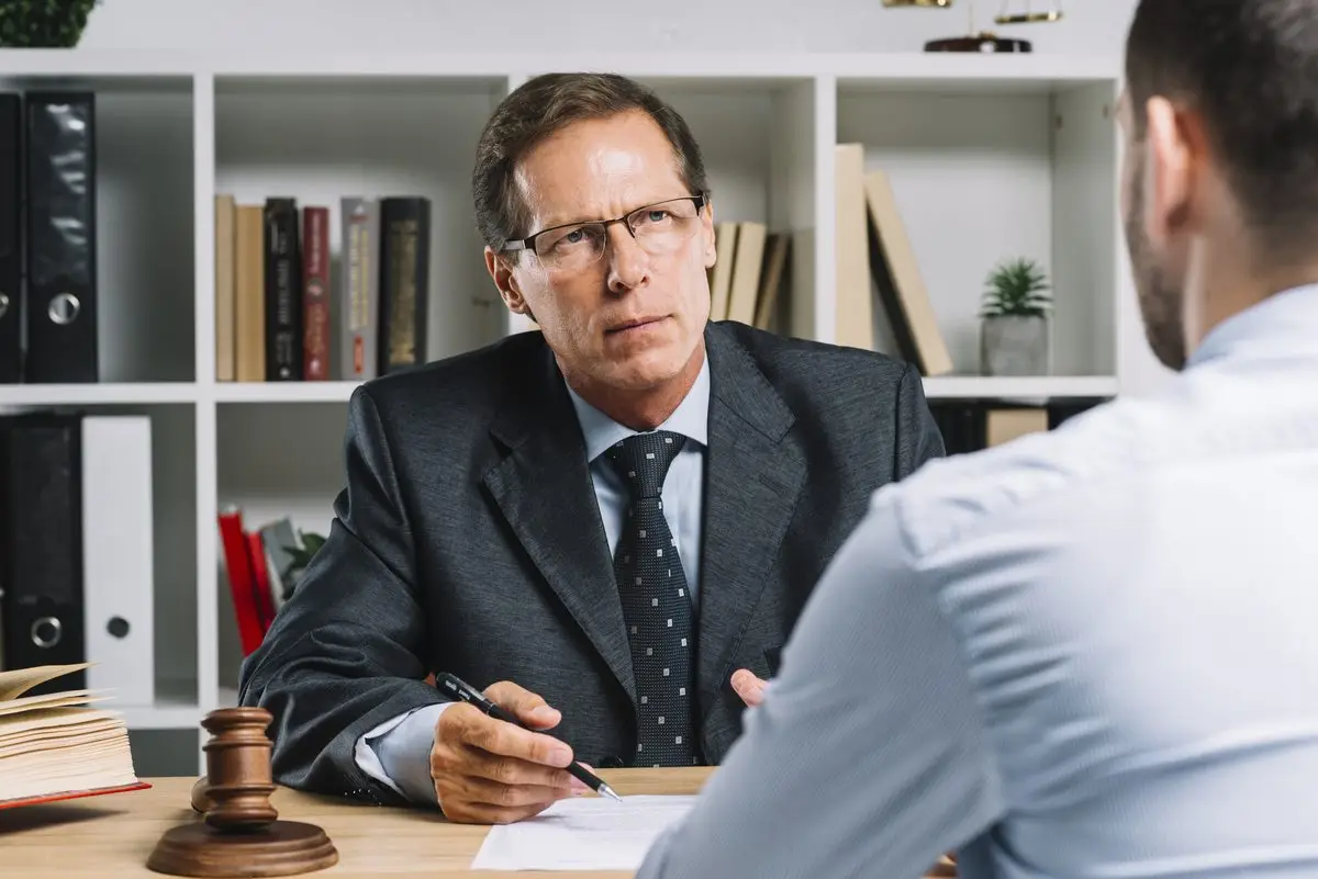 A lawyer in a suit listening carefully to a client across his desk