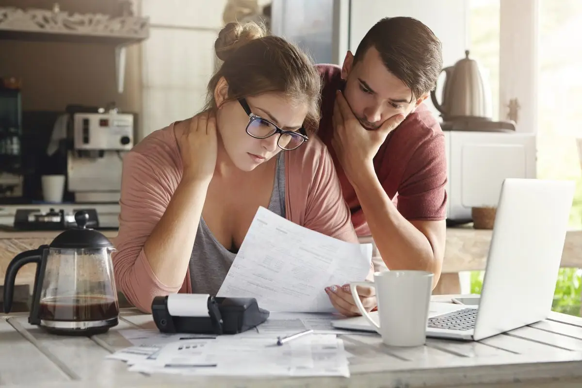 A couple looking worried while going through a bank letter at the kitchen table