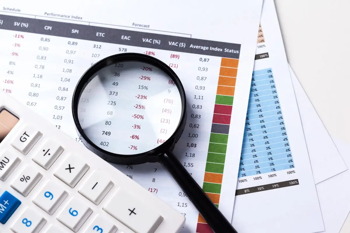 A calculator and magnifying glass over printed financial reports