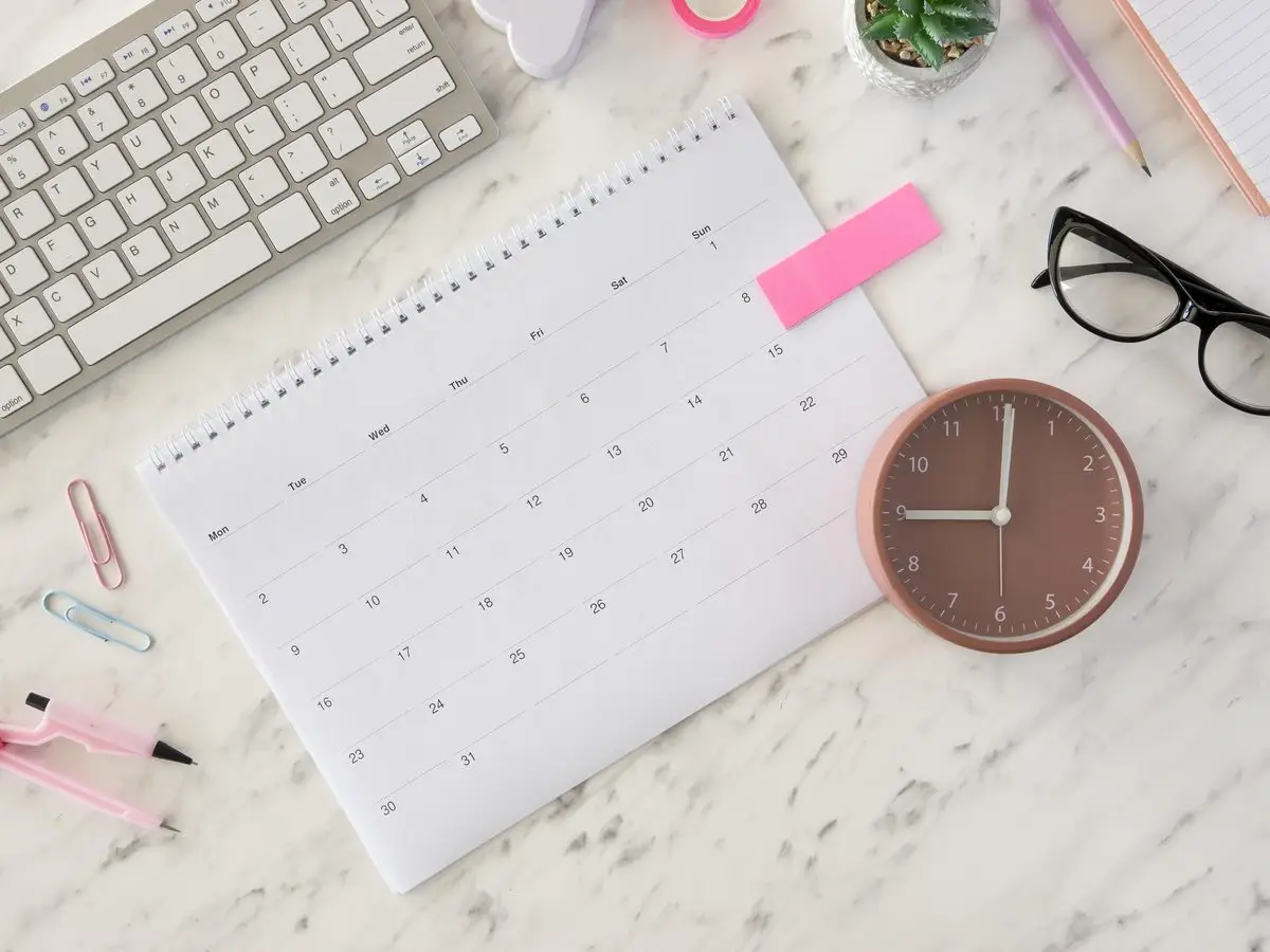A desk calendar and clock on a marble desk, marking a deadline