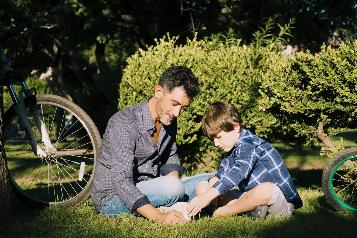 A father and his son sitting together on the grass in a garden