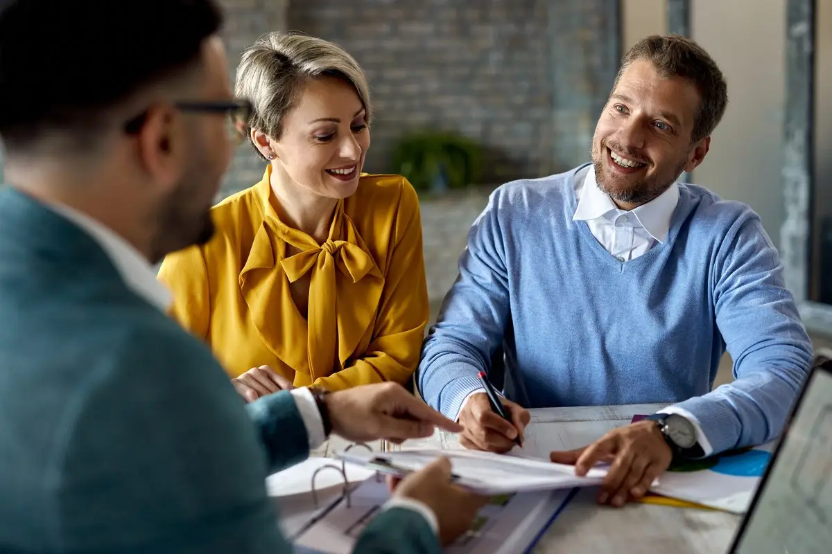 A couple signing an agreement across the table from an adviser