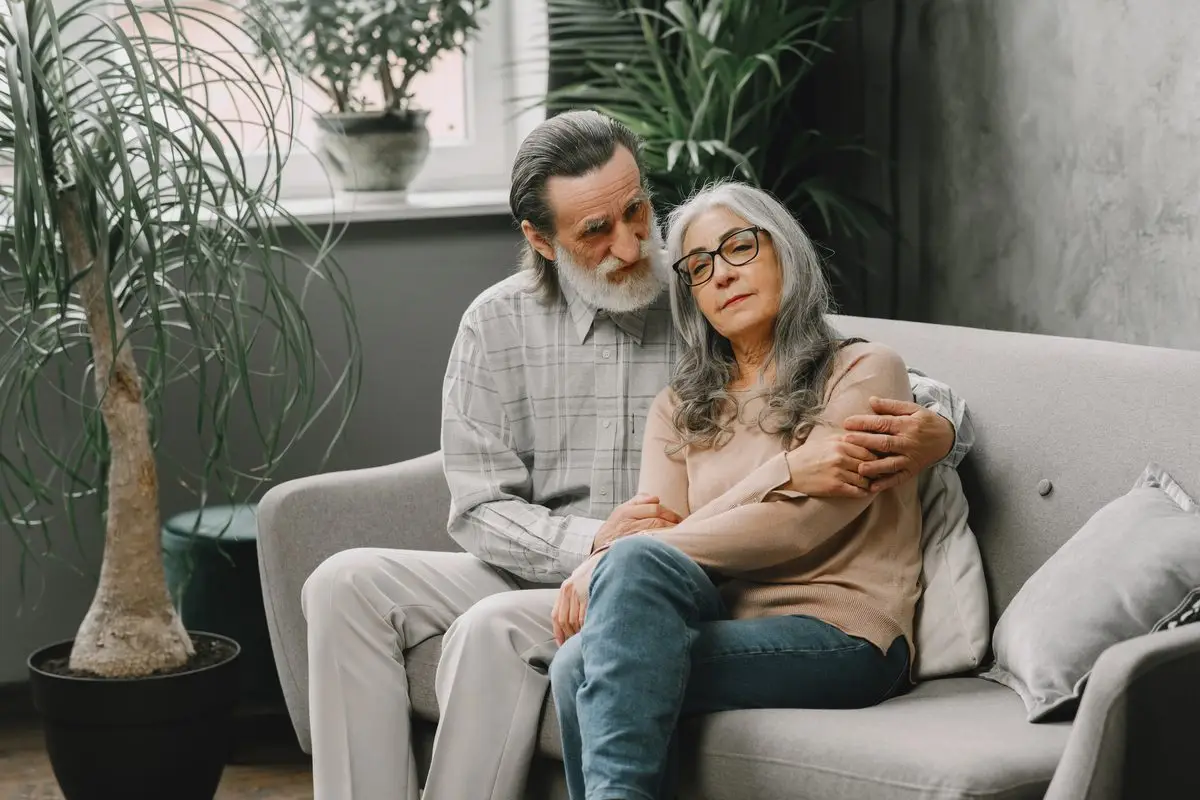 An older couple sitting together on their sofa at home