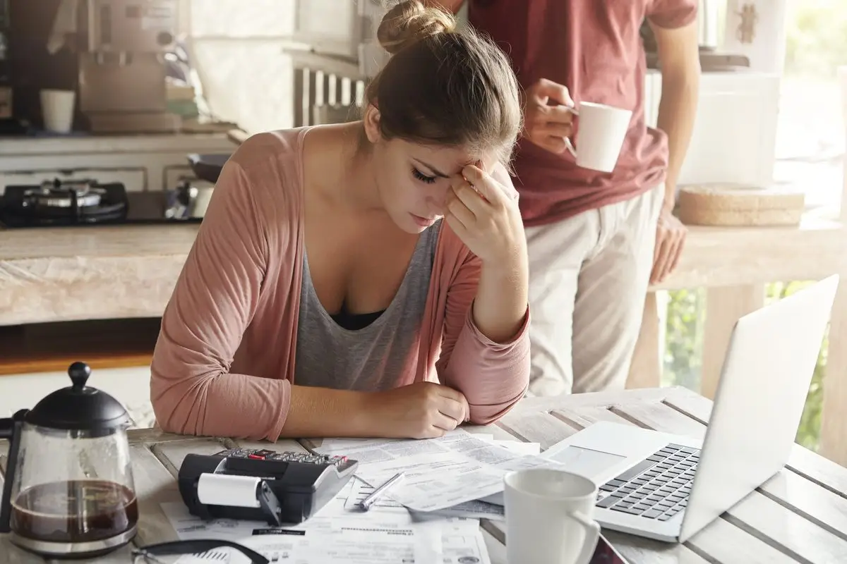A worried woman going through household bills at a kitchen table